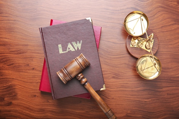 Judge gavel with scales and books on wooden background