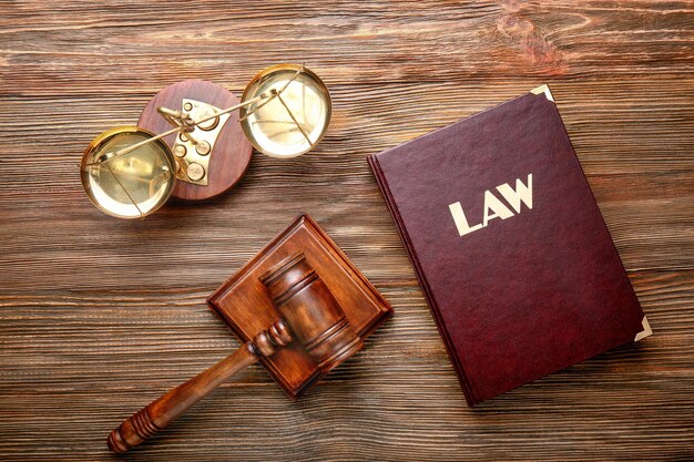 Judge gavel with scales and Law book on wooden background