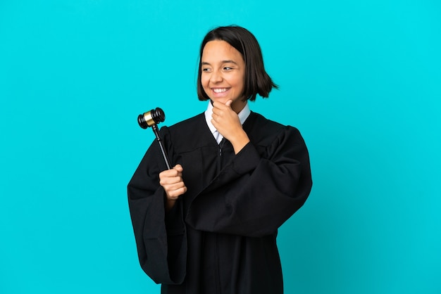 Judge over isolated blue background looking to the side and smiling