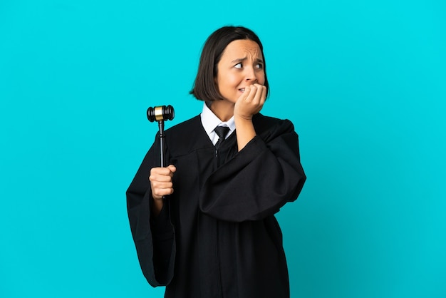 Photo judge over isolated blue background nervous and scared putting hands to mouth