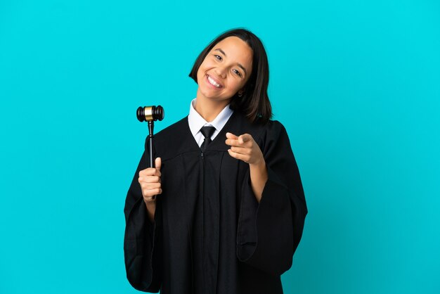 Judge over isolated blue background pointing front with happy expression