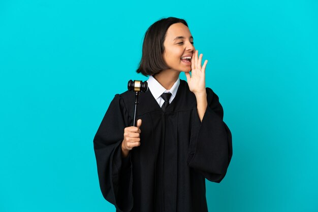 Judge over isolated blue background shouting with mouth wide open to the side