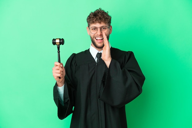 Judge over isolated green background shouting with mouth wide open