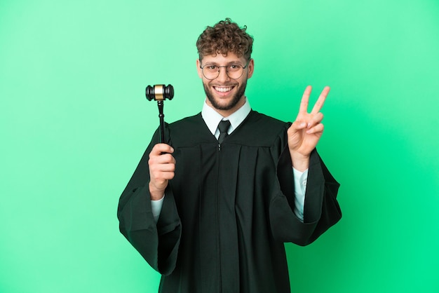 Judge over isolated green background smiling and showing victory sign