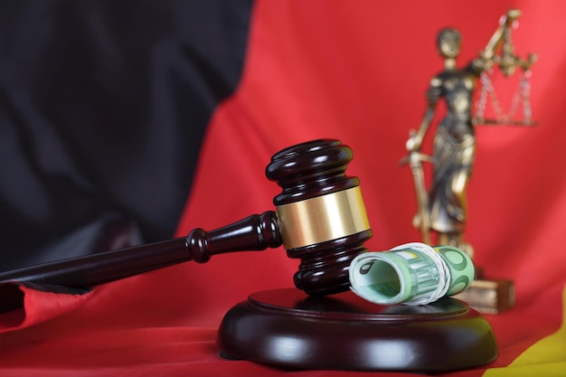 Judge's gavel. Closeup. Flag of Germany and statue of Themis in the background.