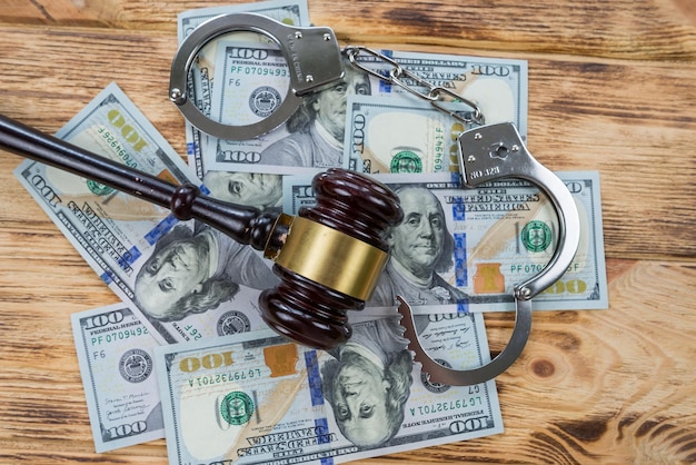 Judge's gavel dollars and handcuffs on a wooden table