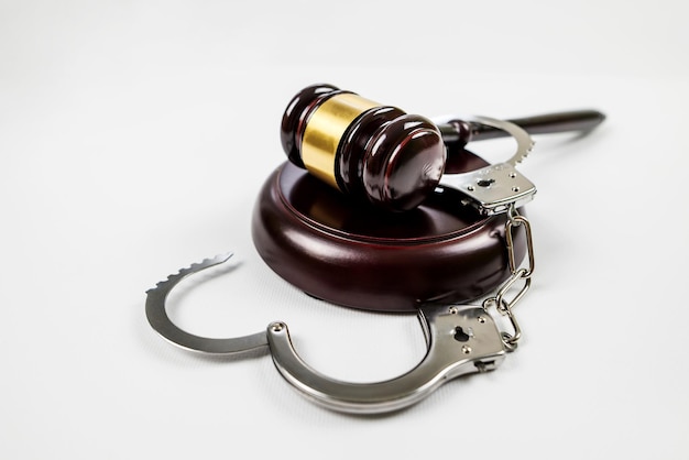 Judge's gavel and handcuffs on a white background