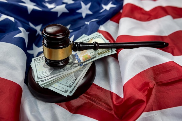 Молоток судьи справедливости помещен вместе с долларами на фоне флага США