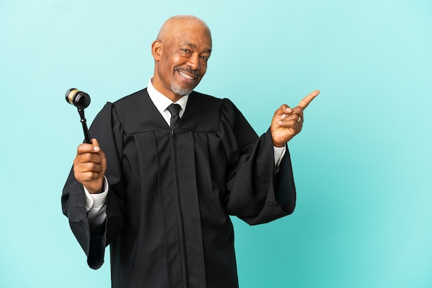 Judge senior man isolated on blue background pointing finger to the side