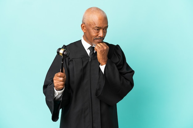 写真 疑いを持って青い背景に孤立した年配の男性裁判官
