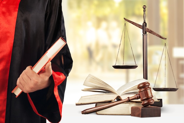 Judge with scale at courtroom, books and wooden gavel