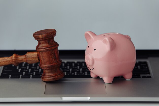 Photo judge wooden gavel and piggy bank on laptop.