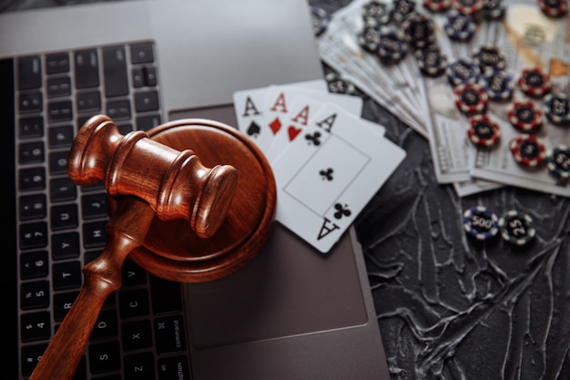 Judge wooden gavel and playing cards on computer keyboard, legal rules for online gambling concept.