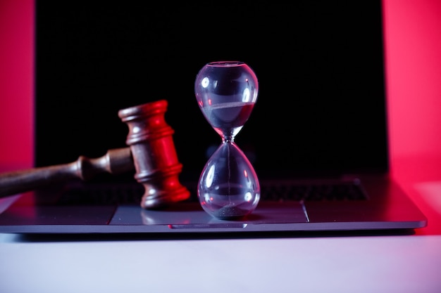 Фото Молоток судей, весы правосудия и песочные часы на ноутбуке.
