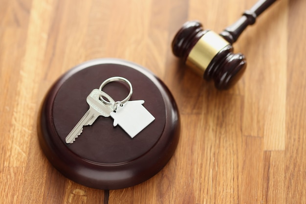 Judges wooden gavel and house keys lying on table. Sale of real estate at auction concept