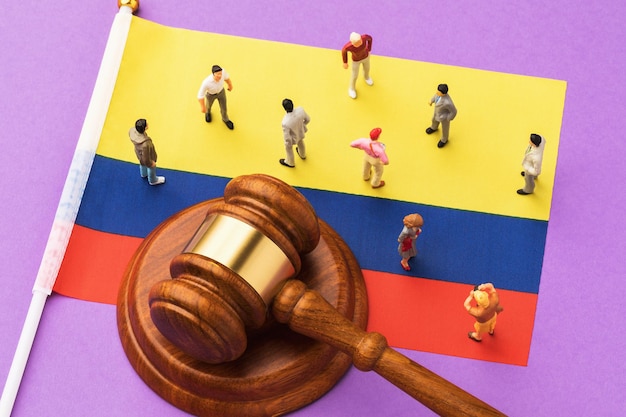 The judicial hammer, the flag of Colombia and toy plastic men on a colored background, the concept of lawsuits in society