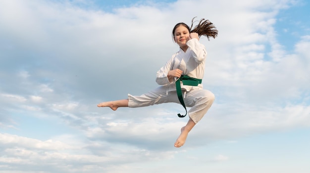 Concetto di judo ragazza adolescente che pratica judo ragazza combattente di judo che salta sullo sfondo del cielo