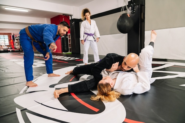 Judo martial arts-partners en een instructeur die nieuwe technieken oefent op een gymnastiekmat