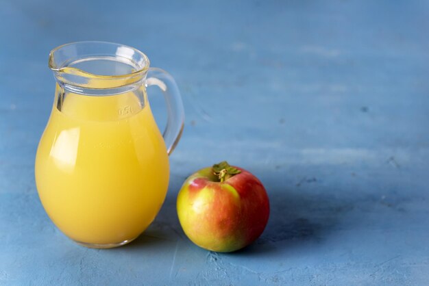 Jug of Apple Juice with Pulp on Blue Background Raw Red Appe Rustic Copy Space