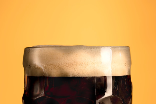 Photo jug of fresh beer with foam on orange background