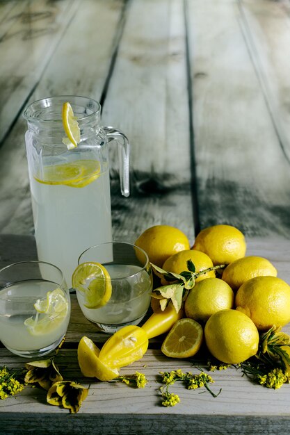 Jug and glasses of lemonade lemons and yellow flowers