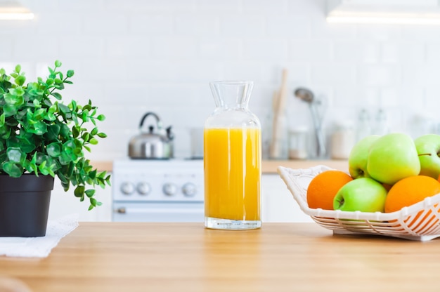 Кувшин апельсинового сока и фруктов на кухонном столе.