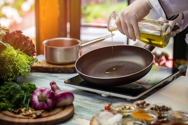 Jug pours liquid on pan green lettuce and purple onion frying pan is warming up need some olive oil