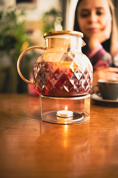 Jug of tea on rack with burning candle