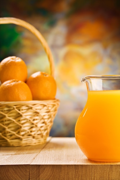 Jug with orange juice and oranges in busket