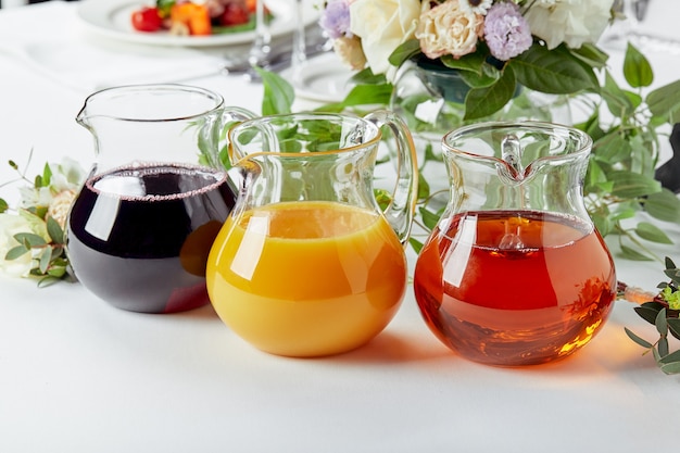 Jugs with different juices on event catering. Apple, orange, cherry and tomato juices.