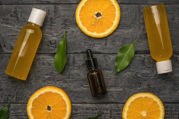 Juice bottles, vials with pipettes and orange slices on a wooden background.