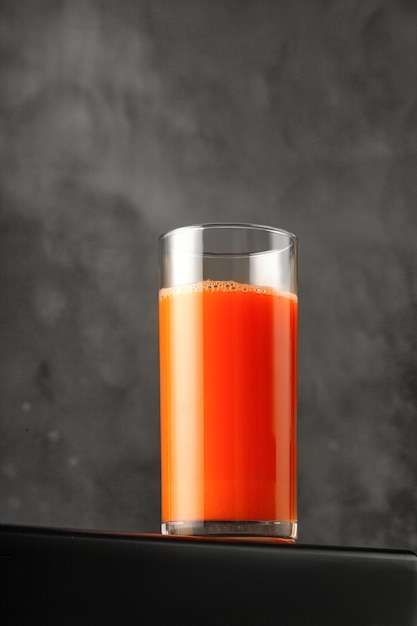 Foto succo di carota in vetro succo appena spremuto su sfondo scuro per il confezionamento e il menu