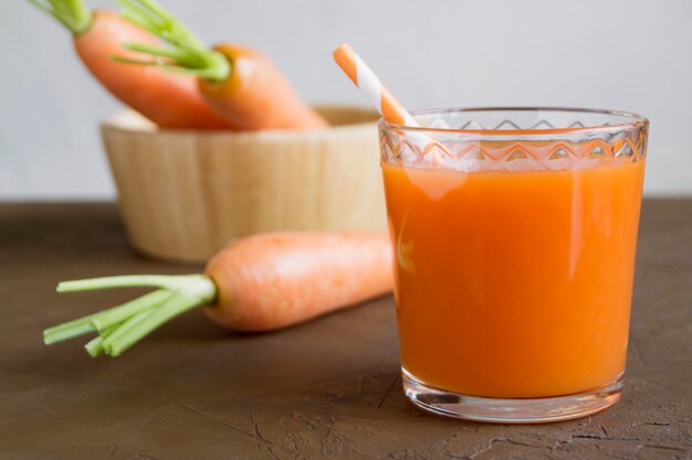 Juice of fresh ripe carrots on a brown background.