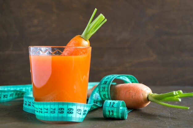 Juice of fresh ripe carrots on a brown background.