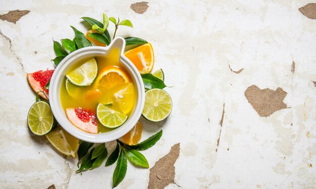 The juice from citrus fruits - grapefruit, orange, tangerine, lemon, lime in a cup with leaves