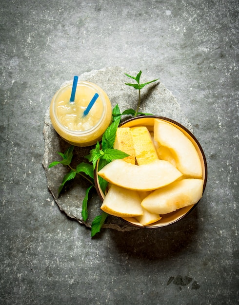 Juice from melons with mint and the pulp. On a stone background.