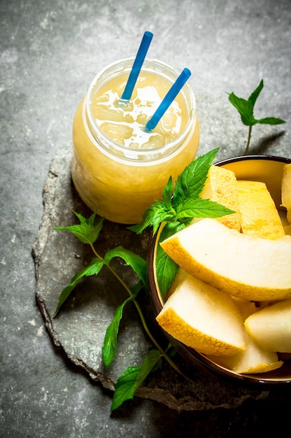 Juice from melons with mint and the pulp. On a stone background.