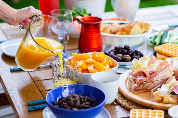 The juice is poured into a glass Orange juice for breakfast Table with food for breakfastOrange