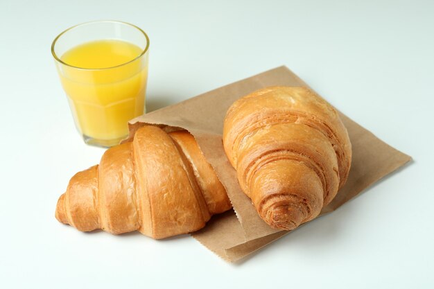 Juice and paper bag with croissants on white