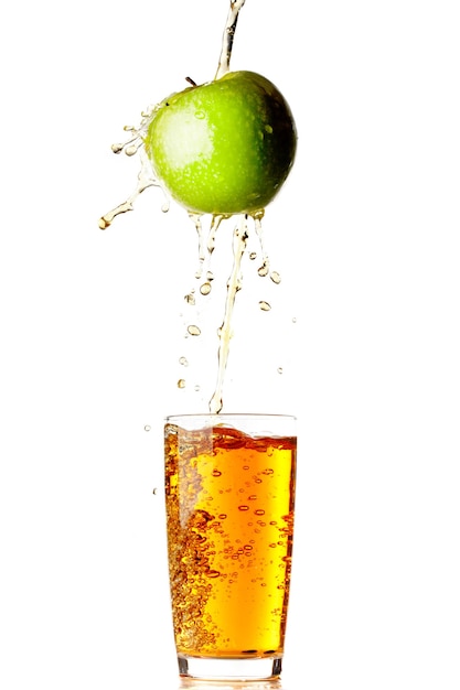 Juice pouring from apple into glass isolated on white wall