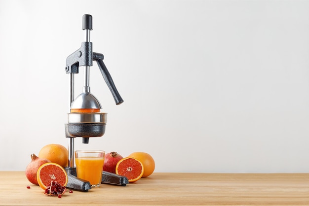 Juicer for citrus fruits with fruits red orange grapefruit pomegranate on wooden table Press juicer