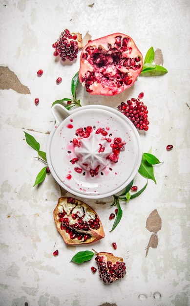 Juicer with bits of pomegranates and leaves. On rustic background. Top view