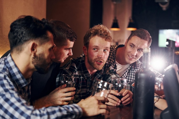 Juichen door op bierglazen te kloppen Groep mensen samen binnen in de kroeg veel plezier in het weekend