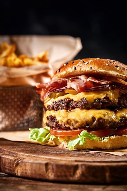 Photo juicy american burger, hamburger or cheeseburger with two beef patties, with sauce and basked on a black background