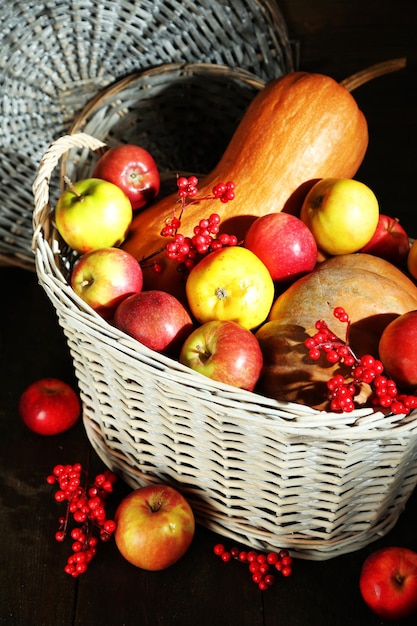 Photo juicy apples and pumpkin in wooden basket on table closeup