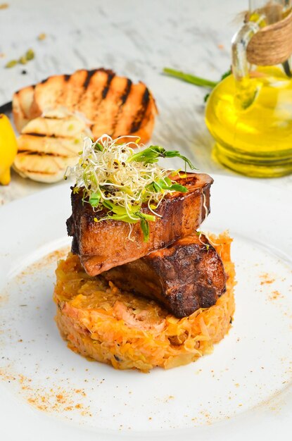 Juicy baked pork ribs with stewed cabbage on a plate Top view