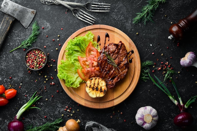 Bistecca di maiale al forno succosa con verdure sulla tavola vista dall'alto