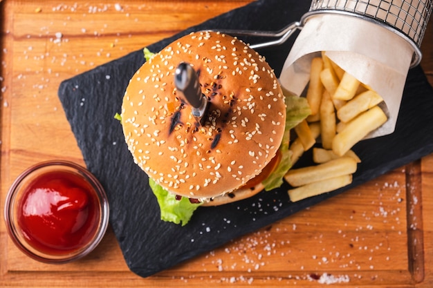 Juicy beef burger with french fries and ketchup on wooden board. top view. fast food