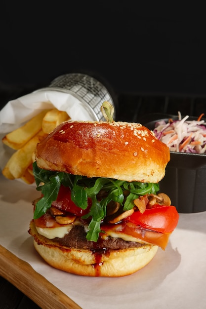 Juicy beef burger with lingonberry sauce, melted cheese, arugula served with fried potato and red cabbage