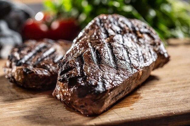 Juicy beef rib eye steak with herbs tomatoes salt and spices.